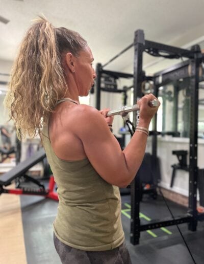 Female athlete lifting a barbell in a gym setting for strength training.