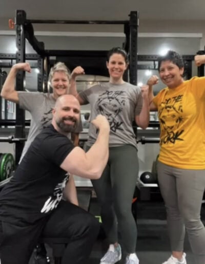 Group of four people flexing muscles in a gym at Revolution Strength & Conditioning.